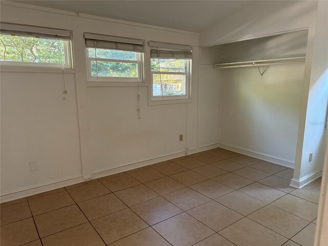1035 NE 3rd Ave, Gainesville, FL 32601 - unfurnished bedroom with light tile patterned floors, a closet, and baseboards