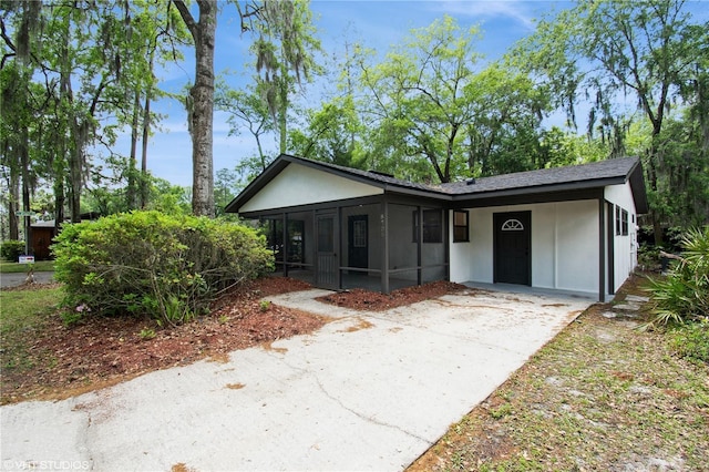 view of front of home featuring concrete driveway, a sunroom, and stucco siding