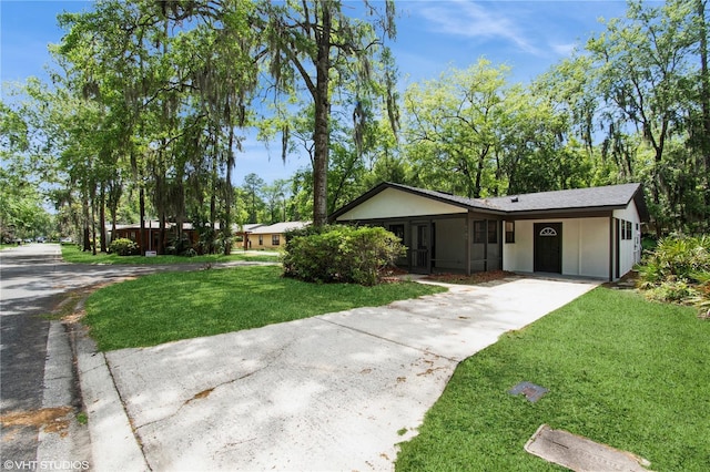 single story home with concrete driveway, a front yard, and stucco siding