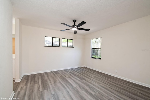 empty room featuring baseboards, a ceiling fan, wood finished floors, and a textured ceiling