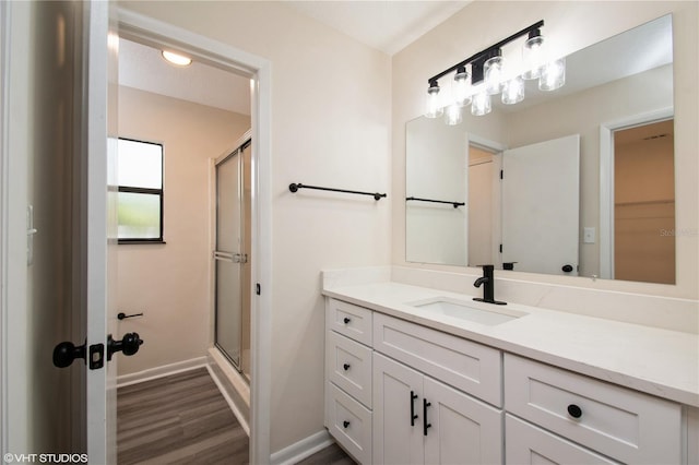 bathroom with baseboards, a stall shower, wood finished floors, and vanity