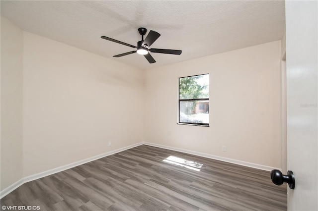 spare room with dark wood-style floors, baseboards, a ceiling fan, and a textured ceiling