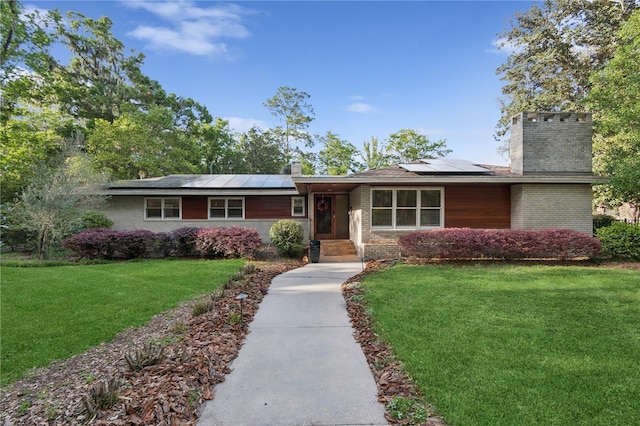 2210 NW 6th Pl, Gainesville, FL 32603 - single story home with a chimney, brick siding, a front lawn, and roof mounted solar panels