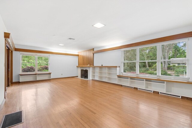 2210 NW 6th Pl, Gainesville, FL 32603 - unfurnished living room featuring light wood finished floors, a fireplace with flush hearth, a baseboard heating unit, and baseboards