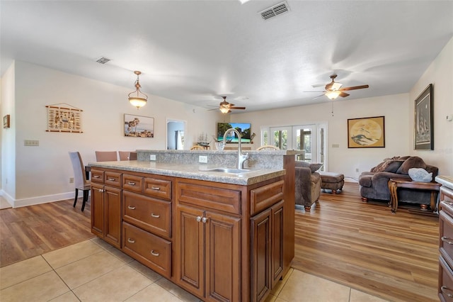 kitchen with ceiling fan, visible vents, a sink, open floor plan, and light wood finished floors