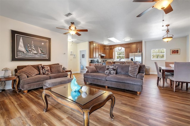 living room with visible vents, baseboards, a ceiling fan, and wood finished floors