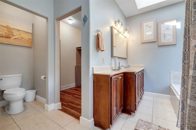 bathroom with toilet, tile patterned floors, vanity, and a skylight