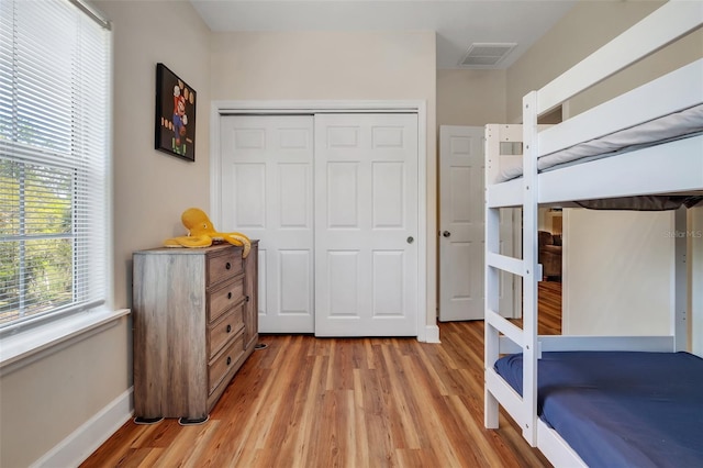 bedroom featuring light wood-style flooring, a closet, baseboards, and visible vents