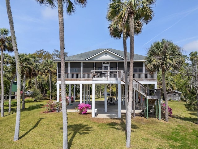 rear view of house with a sunroom, a yard, stairway, a carport, and a shingled roof