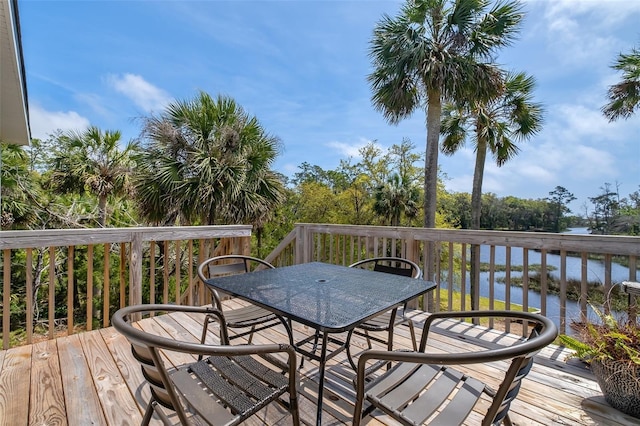 wooden deck with a water view and outdoor dining area