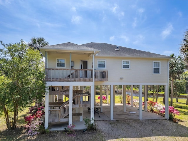back of house with a patio area, stairway, a shingled roof, and a carport