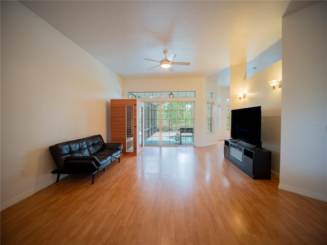 unfurnished living room with light wood-type flooring, a ceiling fan, and baseboards