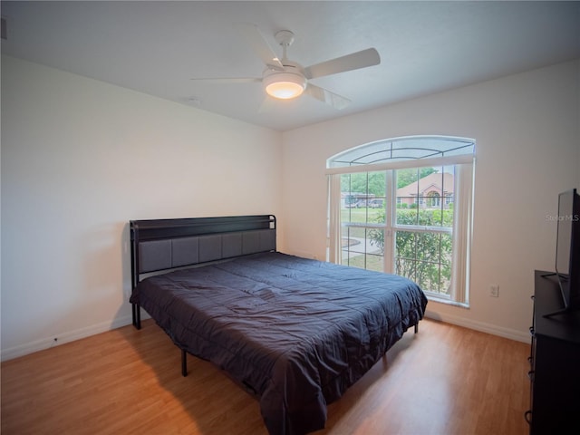bedroom featuring baseboards, light wood finished floors, and a ceiling fan