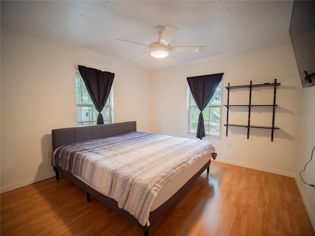 bedroom with light wood-style flooring, multiple windows, and baseboards