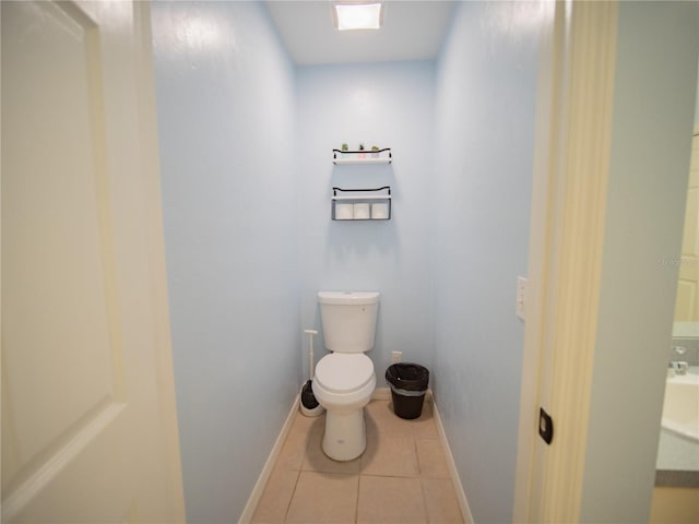 bathroom with tile patterned flooring, baseboards, and toilet