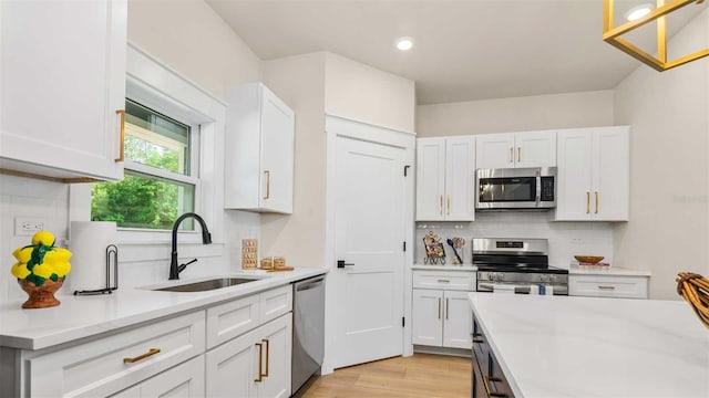 10055 Fox Hollow Dr, Hampton, FL 32044 - kitchen featuring light wood-style floors, white cabinetry, light countertops, a sink, and stainless steel appliances