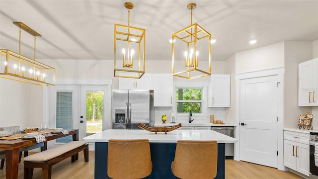 10055 Fox Hollow Dr, Hampton, FL 32044 - kitchen with light countertops, a kitchen island, white cabinets, light wood-style floors, and appliances with stainless steel finishes