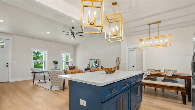 10055 Fox Hollow Dr, Hampton, FL 32044 - kitchen with a center island, light countertops, blue cabinetry, light wood-style floors, and ceiling fan with notable chandelier
