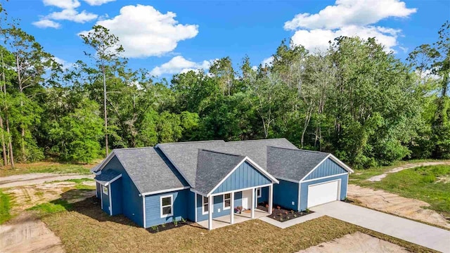 10055 Fox Hollow Dr, Hampton, FL 32044 - view of front of property featuring roof with shingles, driveway, board and batten siding, an attached garage, and covered porch