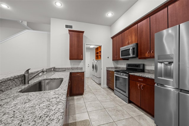 6382 SW 48th Dr, Gainesville, FL 32608 - kitchen featuring appliances with stainless steel finishes, washer and dryer, light stone counters, light tile patterned floors, and recessed lighting