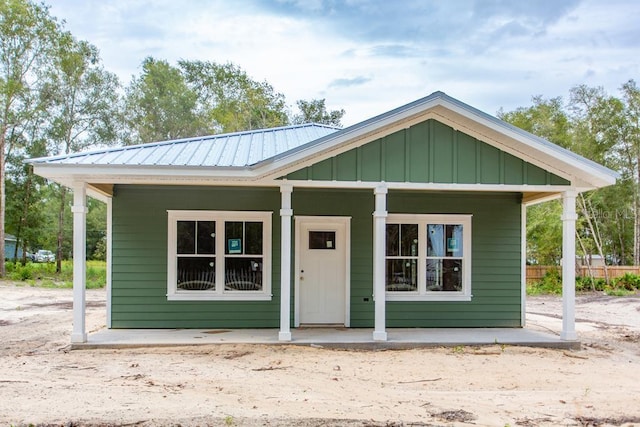 bungalow-style home with metal roof, board and batten siding, and covered porch