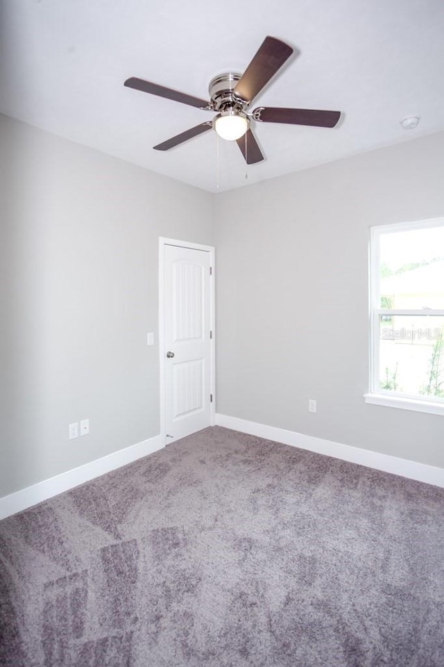 empty room with carpet, baseboards, and a ceiling fan