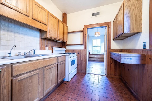 562 NE 2nd Ave, Gainesville, FL 32601 - kitchen with white gas range oven, a wainscoted wall, light countertops, dark tile patterned flooring, and decorative backsplash