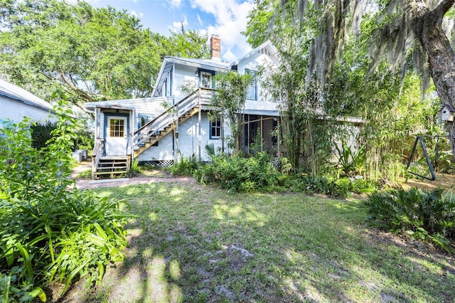 562 NE 2nd Ave, Gainesville, FL 32601 - back of house with stairs, a chimney, and a yard