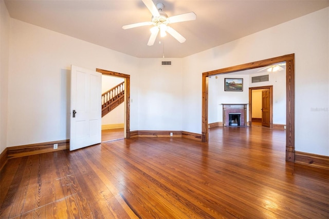 562 NE 2nd Ave, Gainesville, FL 32601 - empty room with wood-type flooring, ceiling fan, a fireplace with flush hearth, and stairway