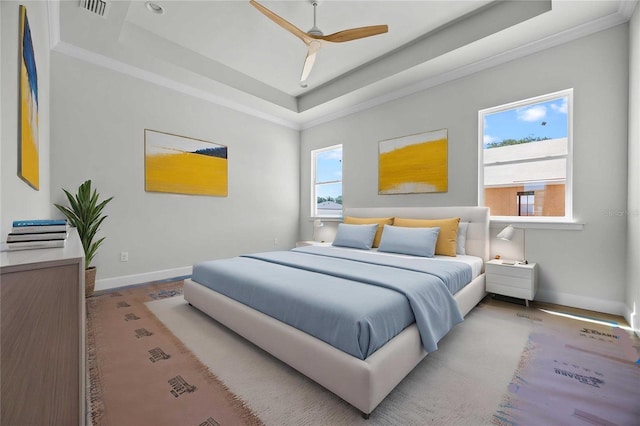 bedroom featuring visible vents, baseboards, a raised ceiling, crown molding, and wood finished floors