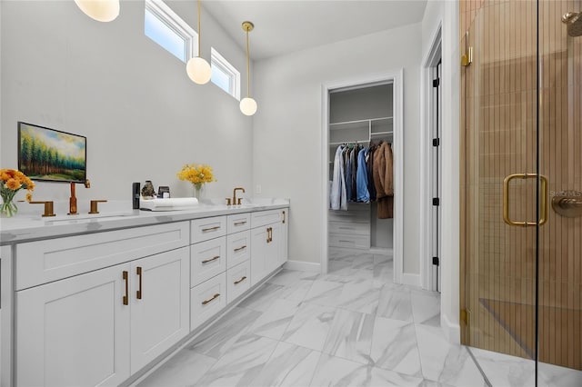 bathroom featuring a sink, a spacious closet, a shower stall, double vanity, and marble finish floor