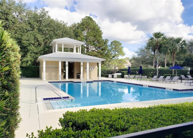 pool with a patio, an outbuilding, and fence