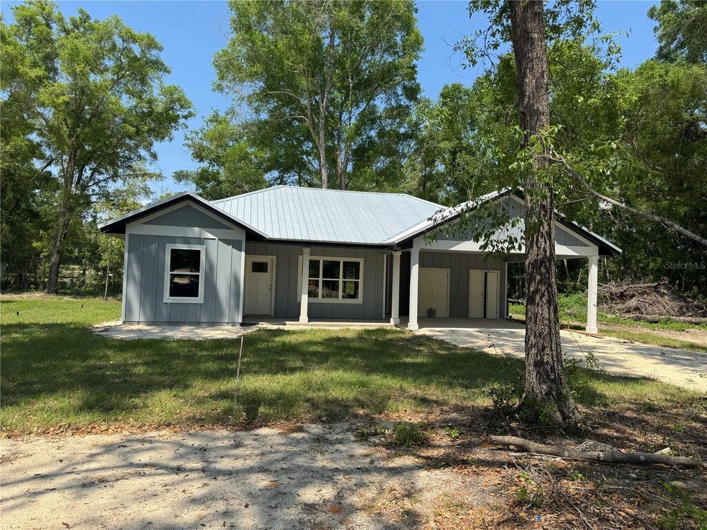 view of front of house with board and batten siding, driveway, a front yard, and a carport