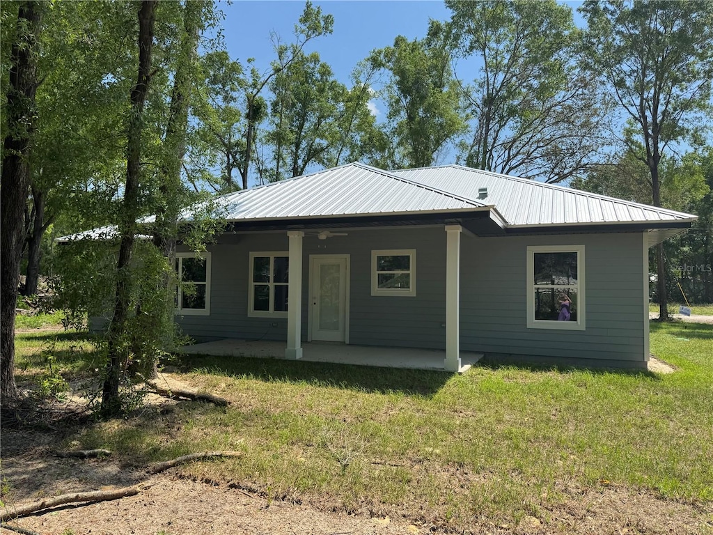 view of front of property featuring metal roof, a front yard, and a patio