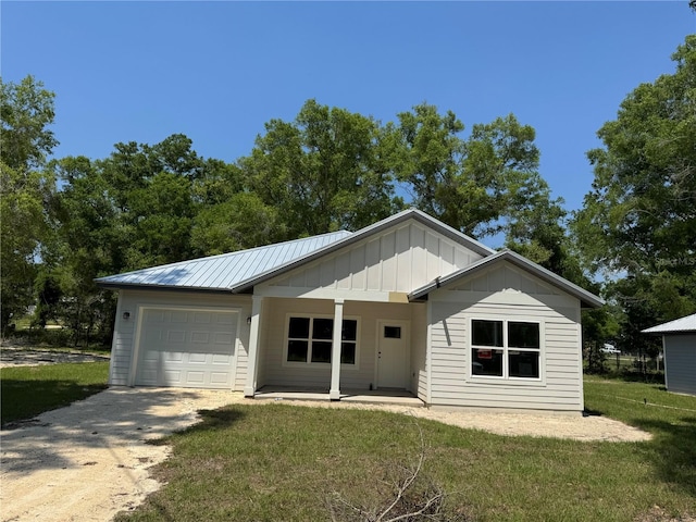 view of front facade featuring board and batten siding, an attached garage, a front yard, and driveway