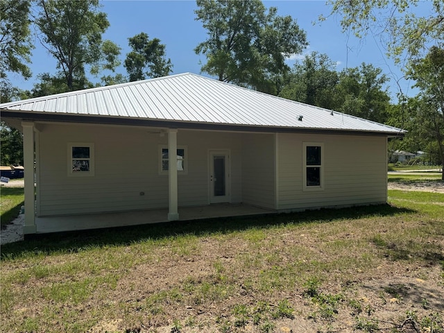 back of house with a patio area, a yard, and metal roof