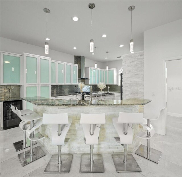 9835 SW 80th Pl, Hampton, FL 32044 - kitchen with light stone counters, wall chimney range hood, a spacious island, beverage cooler, and decorative backsplash