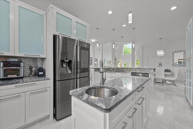 9835 SW 80th Pl, Hampton, FL 32044 - kitchen with glass insert cabinets, stainless steel refrigerator with ice dispenser, a sink, an island with sink, and backsplash