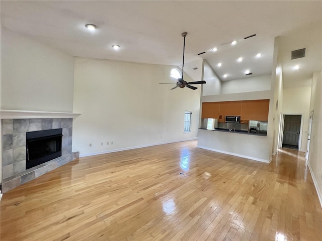 11795 Creek Dr, Alachua, FL 32615 - unfurnished living room featuring light wood-style floors, high vaulted ceiling, ceiling fan, a fireplace, and visible vents