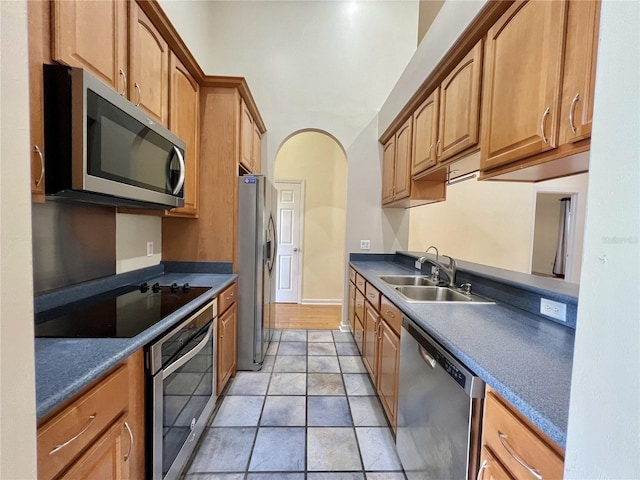 11795 Creek Dr, Alachua, FL 32615 - kitchen with arched walkways, a sink, appliances with stainless steel finishes, dark countertops, and brown cabinets