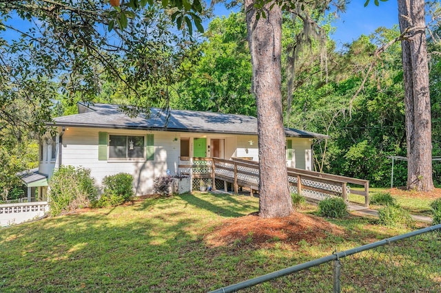ranch-style house featuring a front yard, fence, a shingled roof, and covered porch