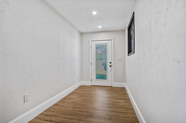 doorway to outside featuring baseboards, wood finished floors, and recessed lighting