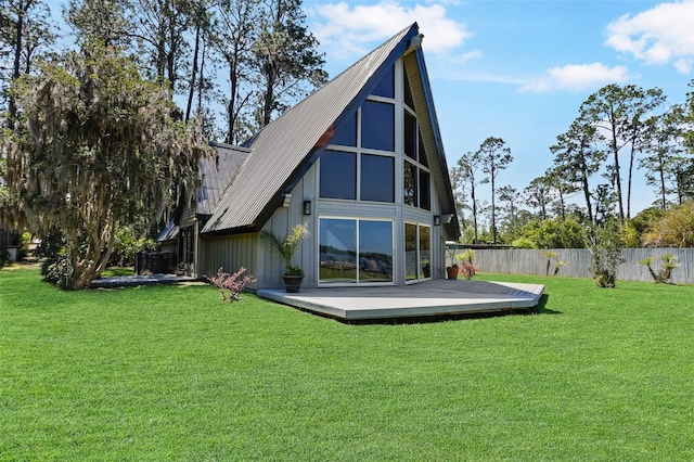 back of house featuring a wooden deck, a lawn, and fence