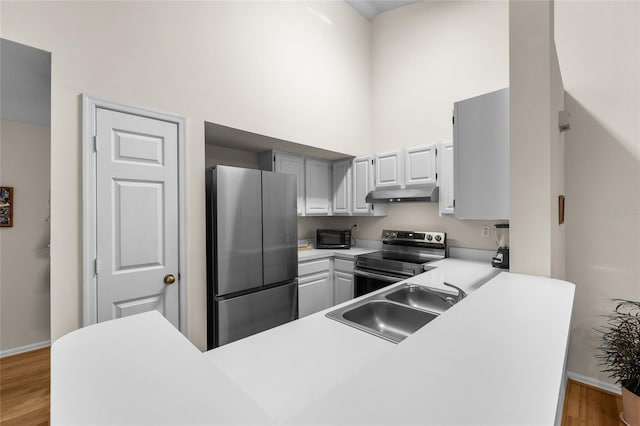10000 SW 52nd Ave Unit 77, Gainesville, FL 32608 - kitchen featuring a towering ceiling, appliances with stainless steel finishes, under cabinet range hood, a sink, and light countertops