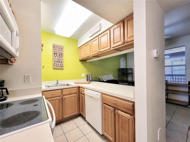 kitchen featuring light countertops, light tile patterned floors, a sink, and white appliances
