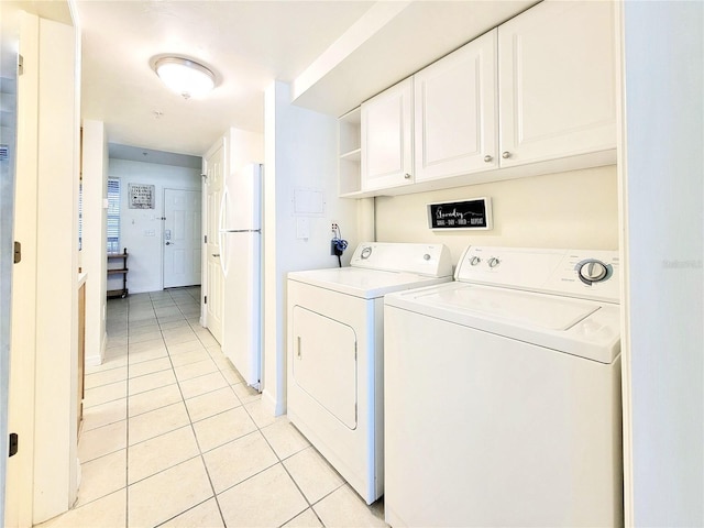washroom featuring washing machine and dryer, light tile patterned floors, and cabinet space