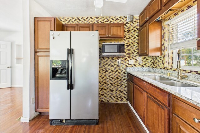 kitchen with fridge with ice dispenser, stainless steel microwave, a sink, and dark wood-style flooring
