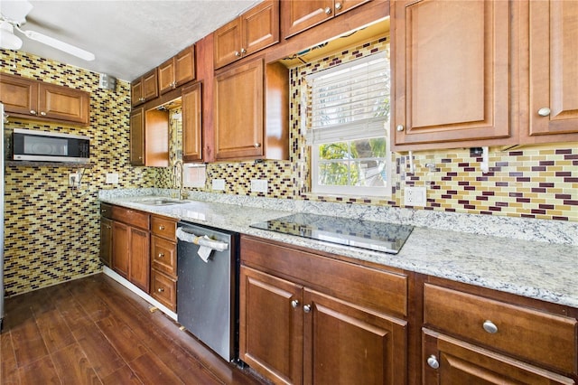 kitchen featuring dark wood-style flooring, backsplash, light stone countertops, appliances with stainless steel finishes, and a sink