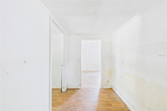 hallway featuring ornamental molding, baseboards, light wood finished floors, and a textured ceiling