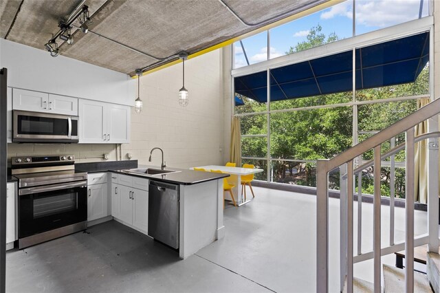 2515 SW 35th Pl Unit 203, Gainesville, FL 32608 - kitchen with appliances with stainless steel finishes, dark countertops, finished concrete floors, concrete block wall, and white cabinetry